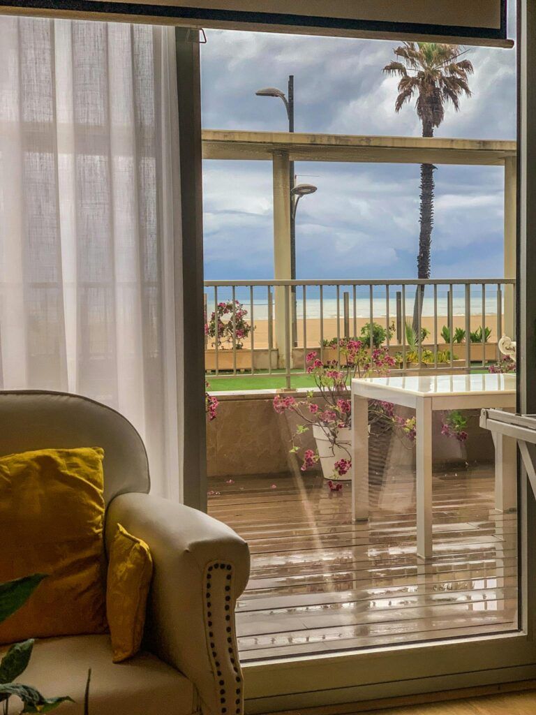 Enjoy a tranquil ocean view through a cozy lounge window with bright decor.